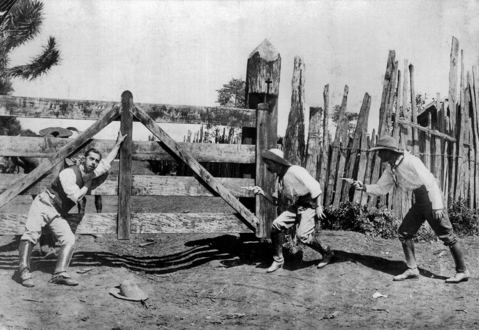 Cena do cinema brasileiro dos anos 1920 mostrando três homens caipiras próximos a uma cerca de madeira